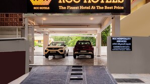 The entrance of RCC Hotels with two cars parked inside, a signboard for RCC Hospitality Services, and a clear view of the outside greenery. - Rcc Hotels Biz stays Begumpet (Hyderabad)