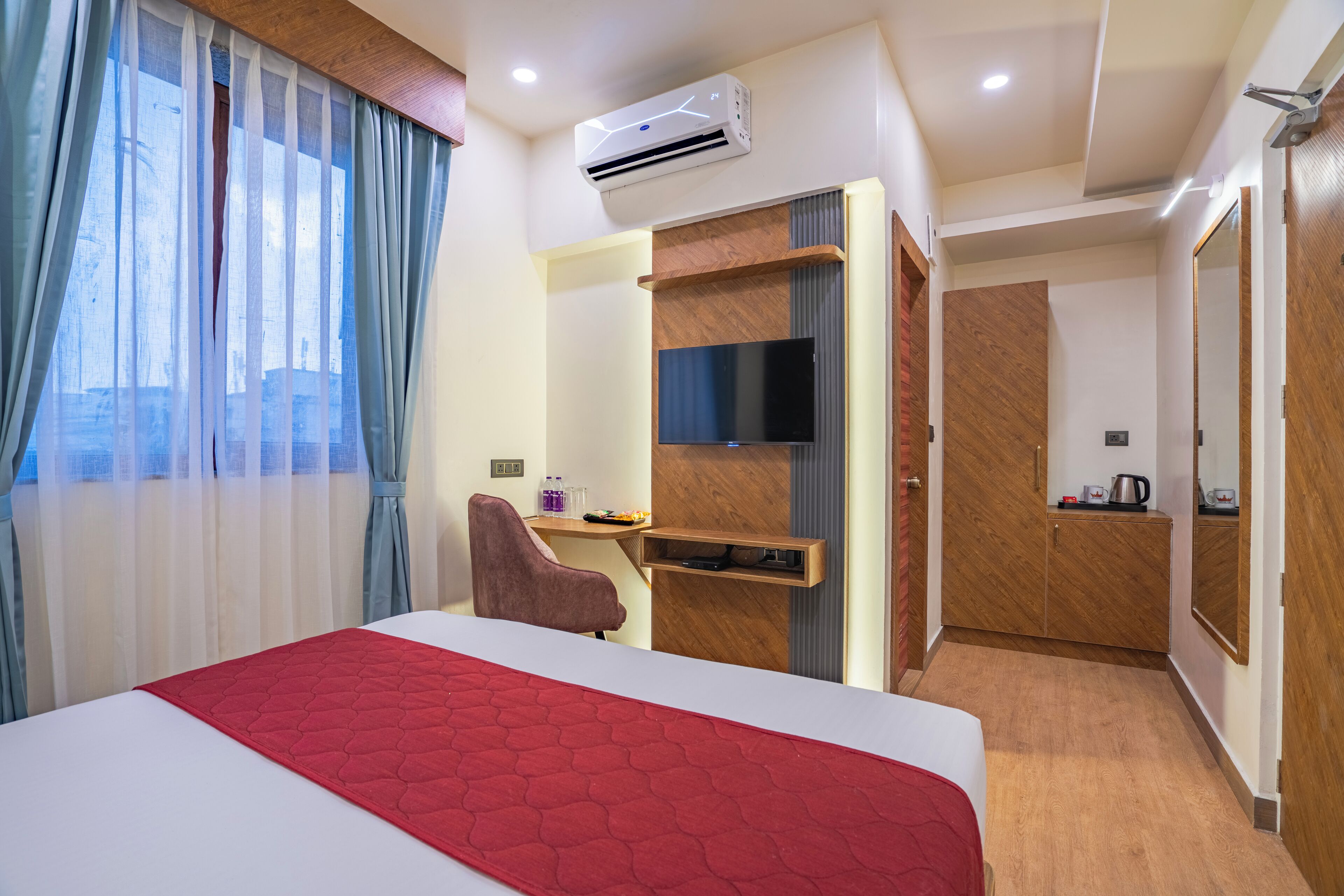 A hotel room with a bed, a desk, a chair, a TV, and a wardrobe.