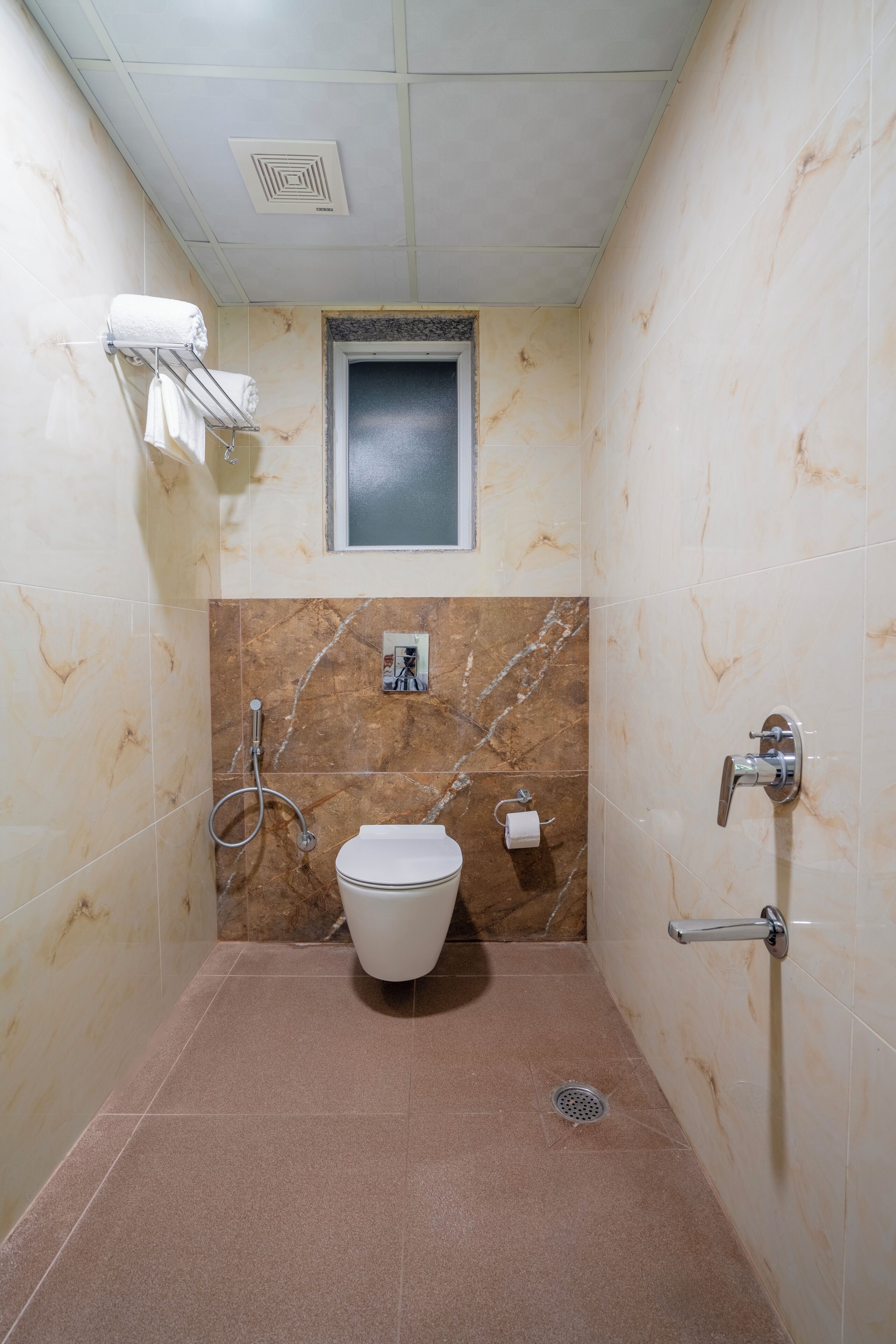 A bathroom with a toilet, a shower, and a towel rack.
