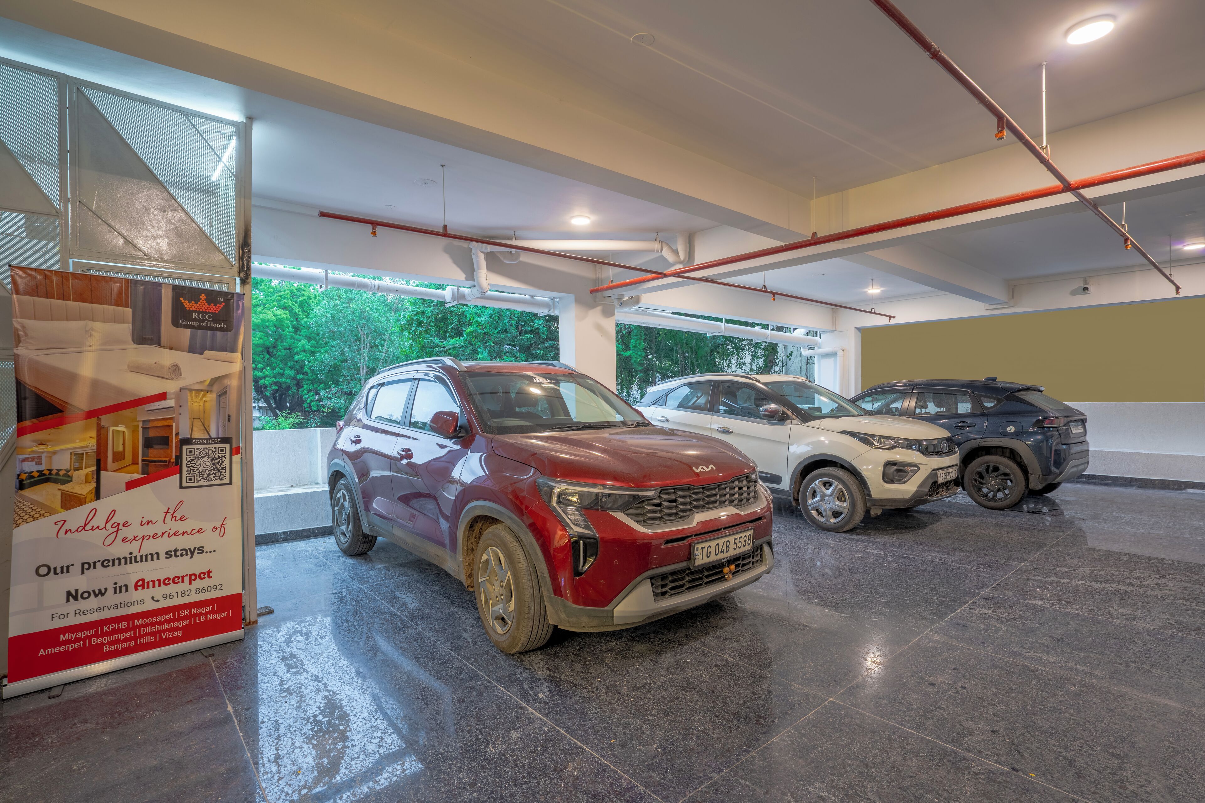 A hotel parking area with a red SUV in the foreground and other vehicles in the background.