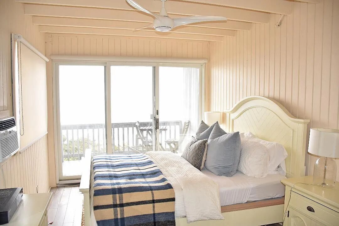 A bedroom with a bed, bedside table, and a ceiling fan.