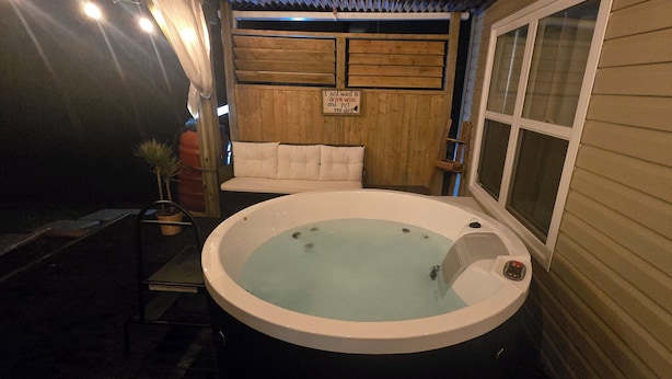 A hot tub with a wooden deck, a bench, and a sign.