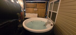 A hot tub with a wooden deck, a bench, and a sign.