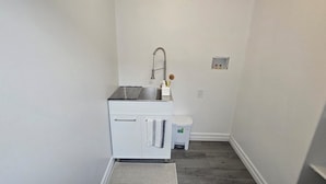 A compact bathroom with a white sink, a small trash bin, and a mirror on the wall.