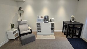 A living room with a sofa, a coffee table, a lamp, a TV, and a dining table with chairs.