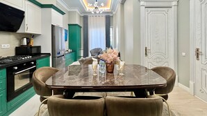 Une cuisine moderne avec un coin repas, comprenant une table en marbre, des chaises confortables et un lustre.