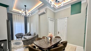 Une salle à manger moderne avec une table en marbre, des chaises rembourrées et un lustre.