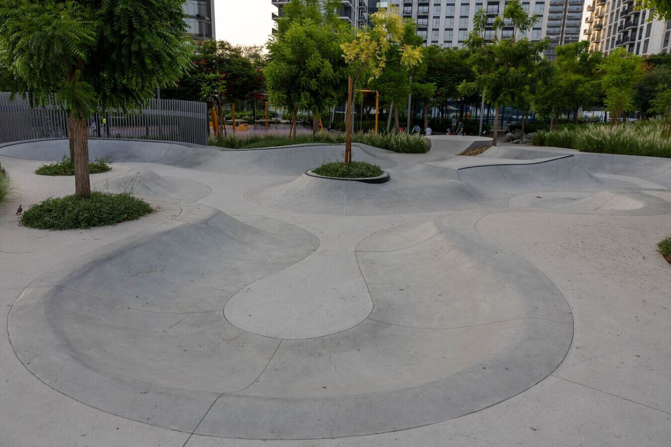 Een modern buitengebied met vloeiende paden en beplanting, omringd door hoge gebouwen.