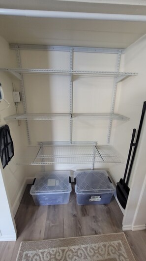 Un cuarto de almacenamiento con estanterías metálicas y dos contenedores de plástico.