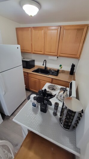 Una cocina compacta con armarios de madera, un refrigerador blanco, un lavamanos y una estufa.
