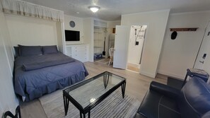 Un dormitorio con cama, televisor, escritorio y silla.