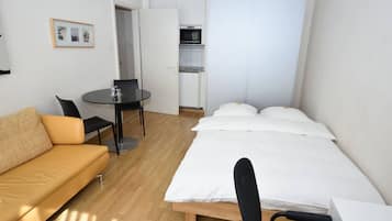 Ein gemütlicher Raum mit Bett, Sofa, kleinem Tisch und Küchenzeile.