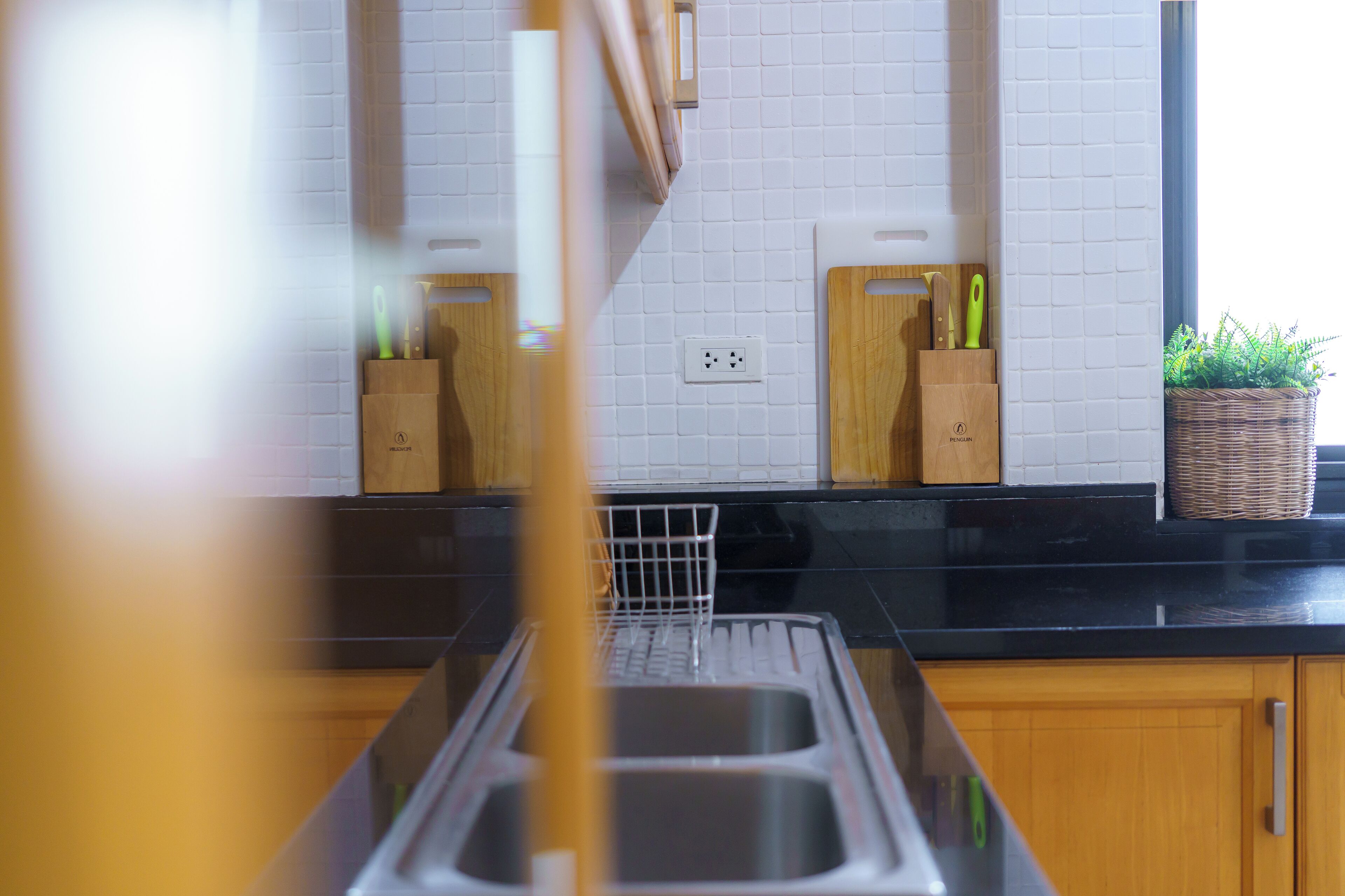 A kitchen with wooden cabinets, a black countertop, and a white tiled backsplash.