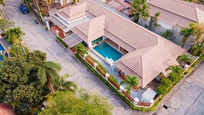 A residential area with multiple houses, a swimming pool, and palm trees. - Natcha villa 41 (Pattaya)