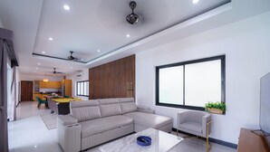 A modern living room with a sectional sofa, a coffee table, a TV, and a large window. - Natcha villa 41 (Pattaya)