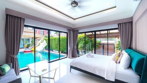 A modern hotel room with a large bed, a glass door leading to a swimming pool, and a balcony with a view of the pool area. - Natcha villa 41 (Pattaya)