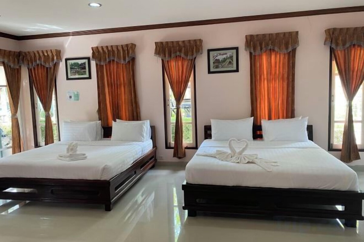 A hotel room with two beds, large windows, and curtains.
