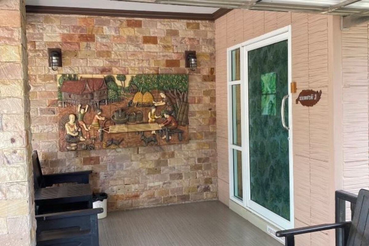 A stone wall with a mural, a glass door, and a bench.
