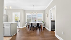 A kitchen with a white fridge, a dining table with chairs, and a window with blinds.