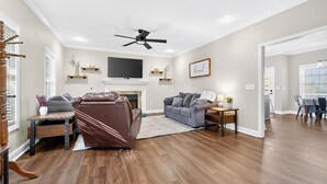 A spacious living room with a fireplace, leather sofa, and a flat-screen TV.