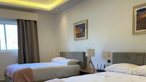 A hotel room with two beds, a ceiling fan, a nightstand with a lamp, and a painting on the wall. - Studio with beach and pool access at Club Cadaqués, Bayahibe (San Rafael de Yuma)