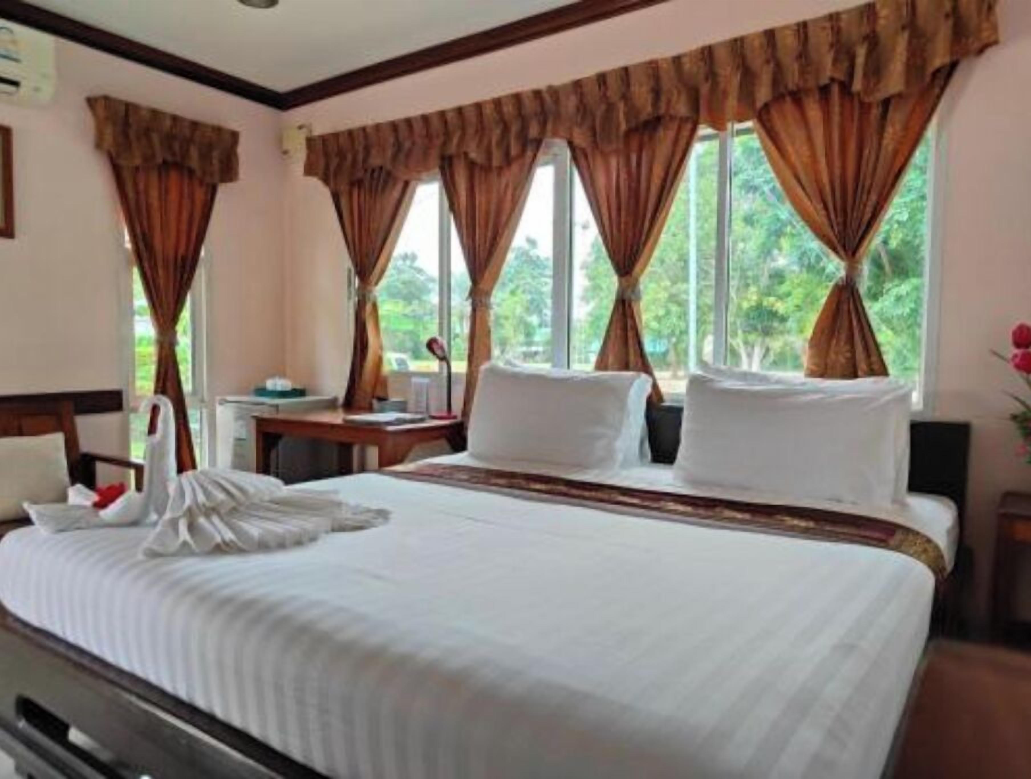 A hotel room with a bed, a desk, and curtains.