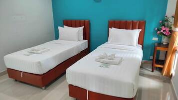 Two twin beds with white linens and red headboards in a room with teal walls.