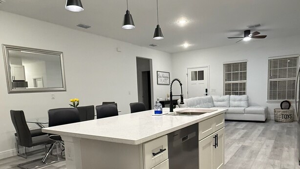 Una cocina moderna con una isla central, iluminación colgante y un ventilador de techo.