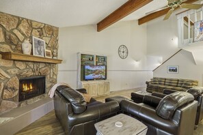 A living room with a stone fireplace, leather sofas, a television, and a clock on the wall. - Last-Min Summer Escape! 15% Off Your August Stay. Must Book By 8/17/26. (Pagosa Springs)