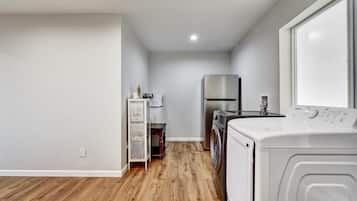A laundry room with a washing machine, dryer, and stacked appliances on shelves.