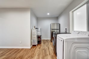 A laundry room with a washing machine, dryer, and stacked appliances on shelves.