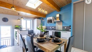 Eine moderne Küche mit Holzbalken, einer blauen Akzentwand und einem Essbereich mit einem Holztisch, gedeckt für vier Personen.
