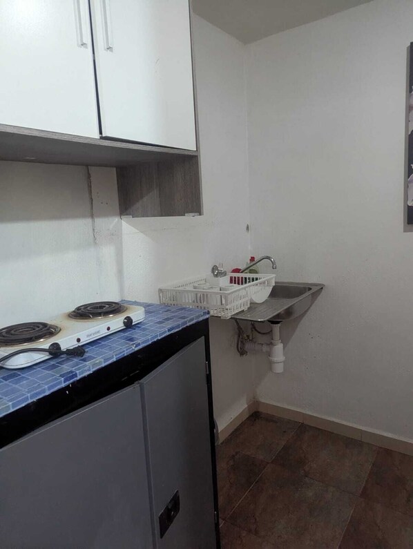 A compact kitchen with a gas stove, a small sink, and a white cabinet.