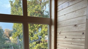 Ein Holzinnenraum mit einem Fenster, einem Stuhl mit gemustertem Sitzkissen und einem Tisch.