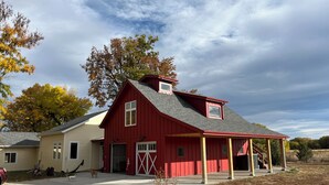 Ein rot gestrichenes, barn-ähnliches Haus mit überdachter Veranda und Garage.