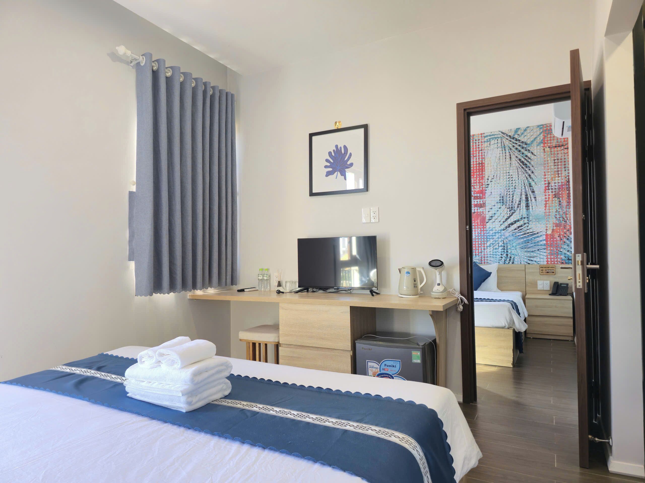 Une chambre d’hôtel comprenant un lit, un bureau avec une télévision, une bouilloire et un petit placard.