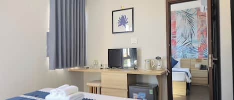 Ein Hotelzimmer mit einem Bett, einem Schreibtisch mit Fernseher, einem Wasserkocher und einem kleinen Schrank.