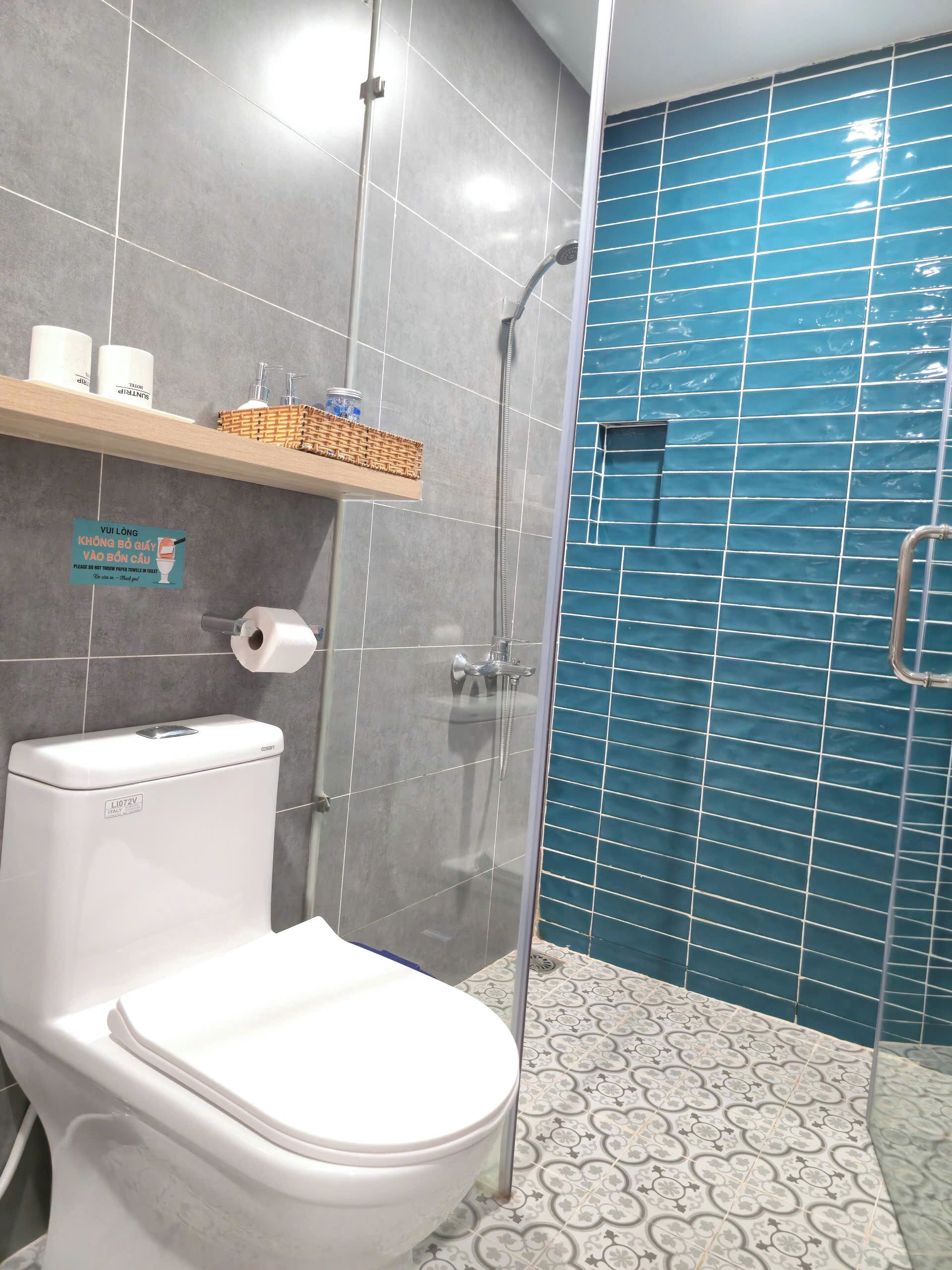 Un bagno con il water, una doccia e una parete piastrellata di blu.