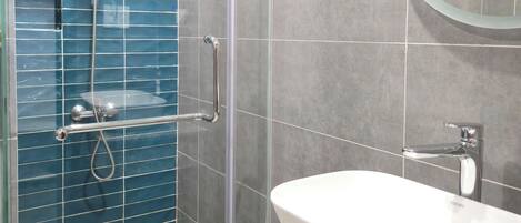 Une salle de bain moderne avec une douche à parois de verre, un lavabo blanc et un comptoir en granit.