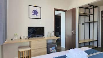 Habitació d'hotel amb llit, escriptori amb televisió, barra minibar i armari.