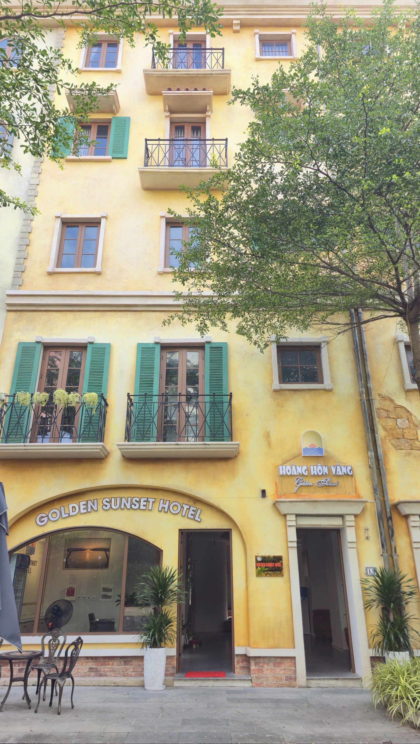Um edifício amarelo com a placa do Hotel Golden Sunset.