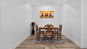 A dining area with a wooden table and chairs, a rug, and a painting on the wall. - Spacious 2 bedroom unit in North Edmonton. (Edmonton)