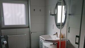 A modern bathroom with a toilet, sink, and shower. - Vacation apartment in a quiet location (Friedrichsthal)