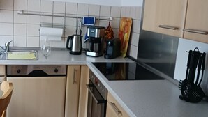A kitchen with a clock, coffee maker, toaster, and a stove. - Vacation apartment in a quiet location (Friedrichsthal)