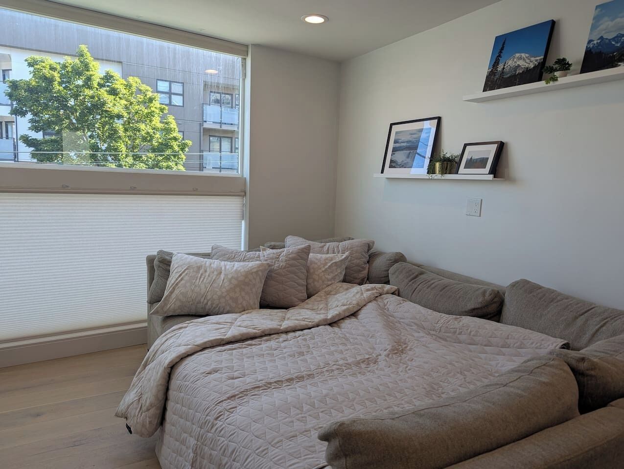 Un dormitorio con una cama grande, una ventana con persianas y una pared decorada con cuadros.