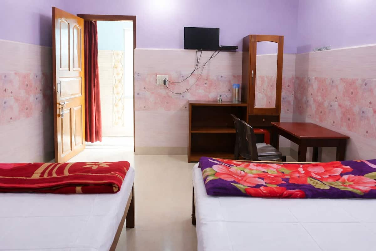 A bedroom with two beds, a desk, a chair, a TV, and a wardrobe.