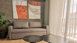 A modern living room with a grey sofa, two black round tables, and abstract artwork on the wall.