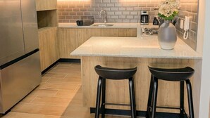 A modern kitchen with a central island, stainless steel appliances, and a tiled backsplash.