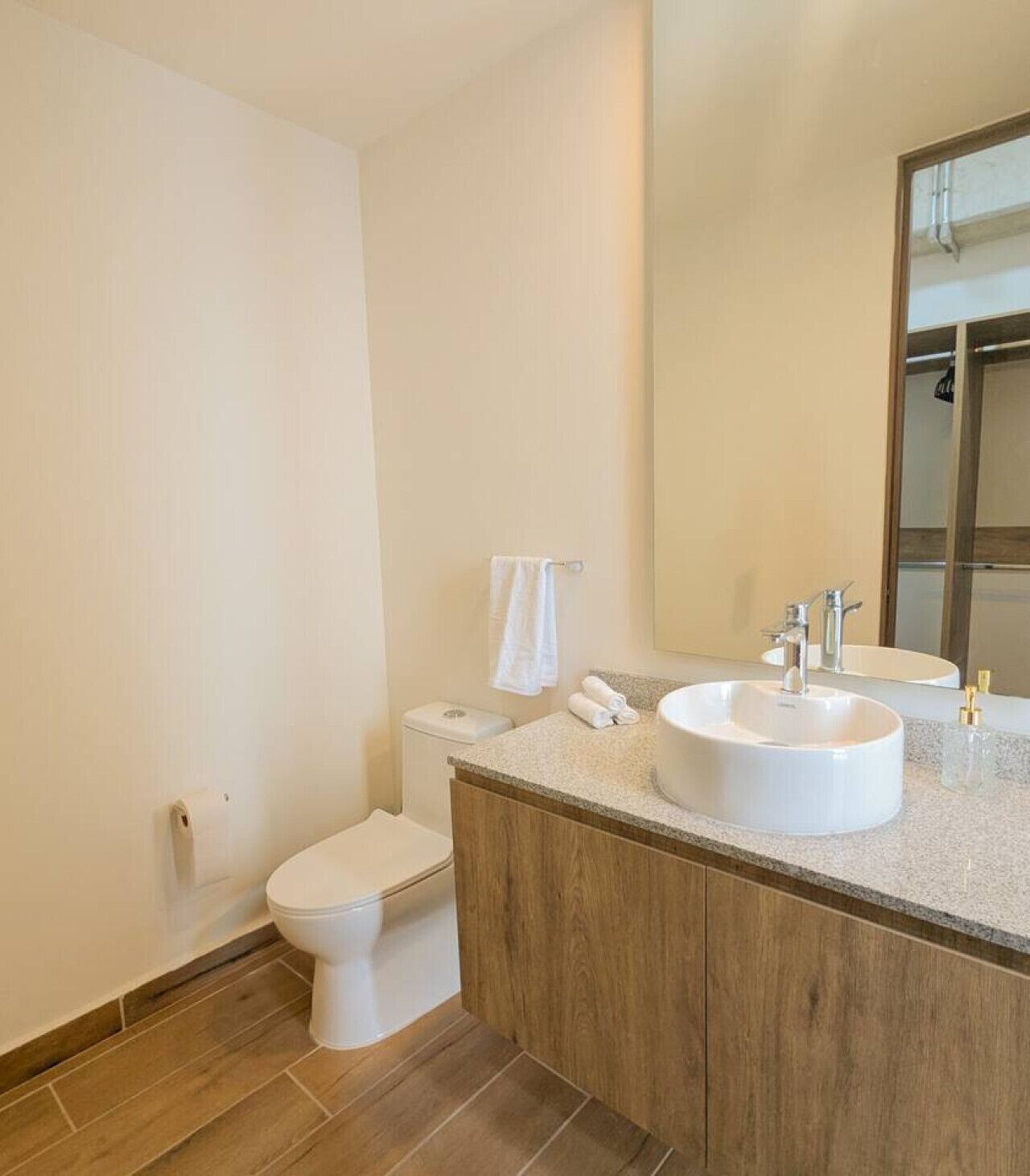 A modern bathroom with a toilet, a sink, and a mirror.
