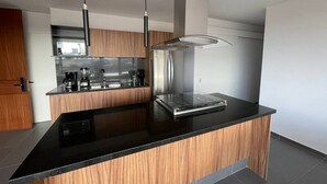 A modern kitchen with a central island, stainless steel appliances, and wooden cabinetry.
